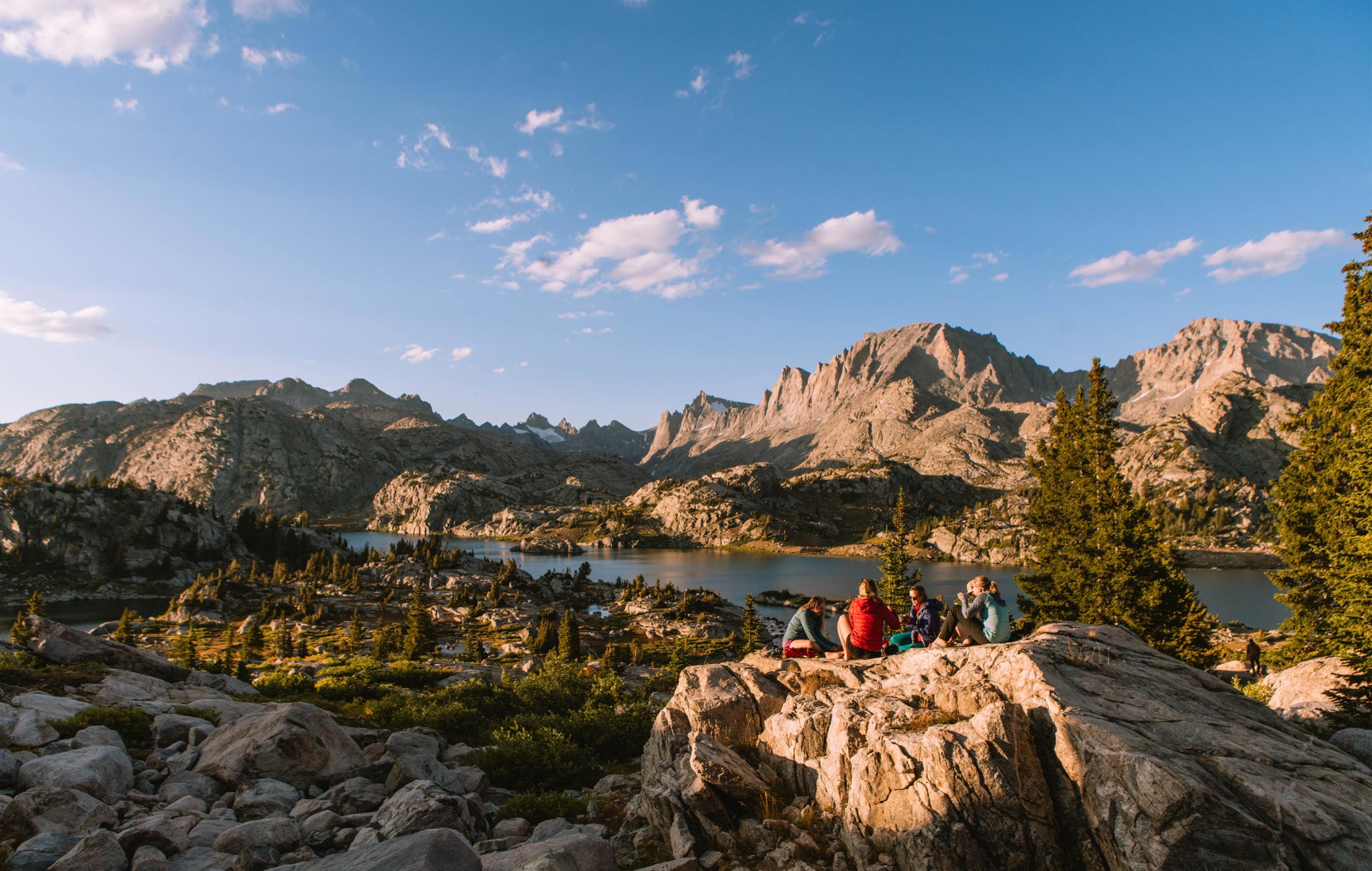 New-Thought-Visit-Pinedale-Wyoming-Ad-Photography-Friends-Sit-On-Rock-Wind-River-Rang-Backcounty-Lake-fullscreen