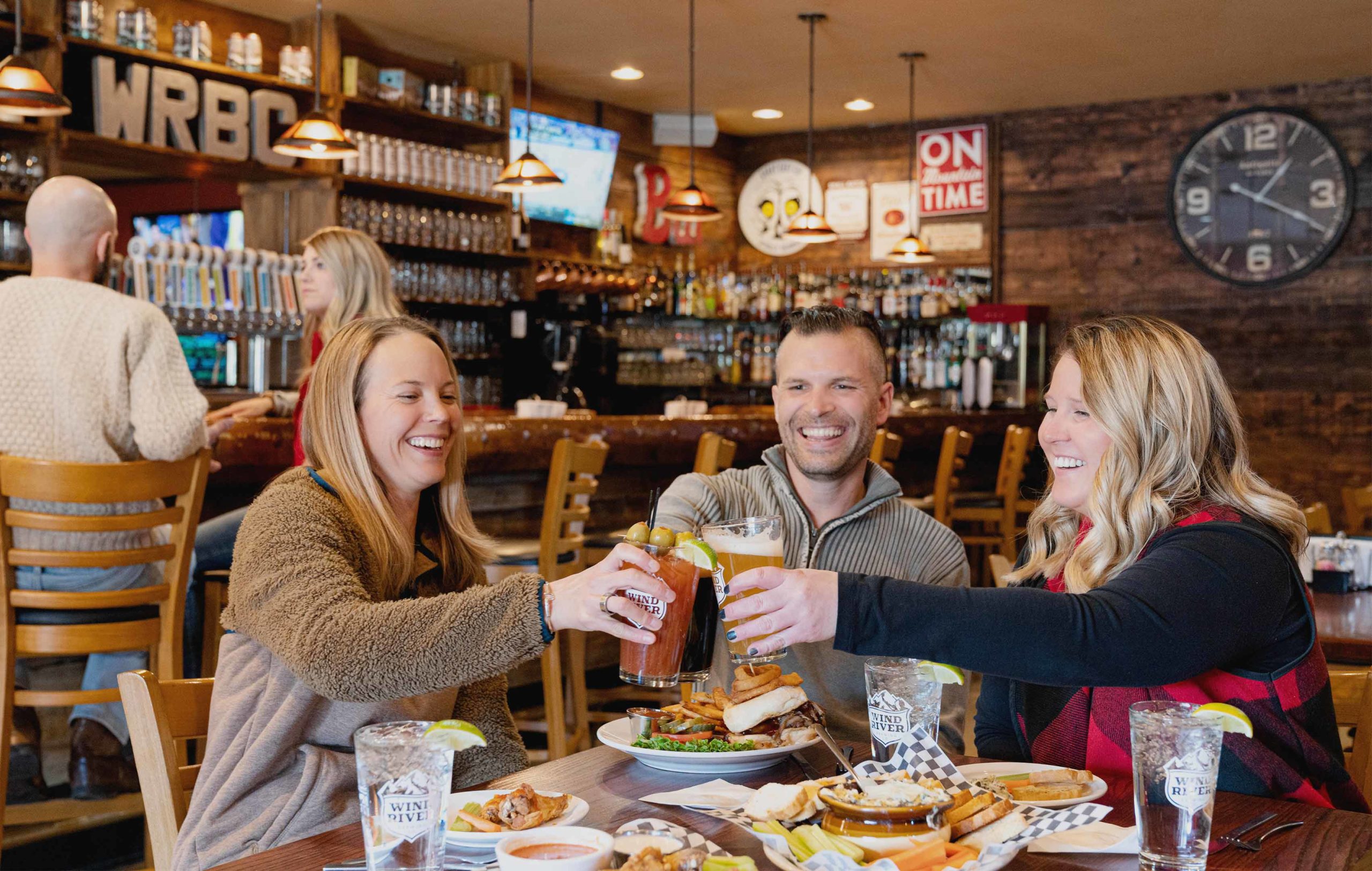 New-Thought-Visit-Pinedale-Wyoming-Ad-Photography-Three-Friends-Cheers-At-Wind-River-Brewing-fullscreen